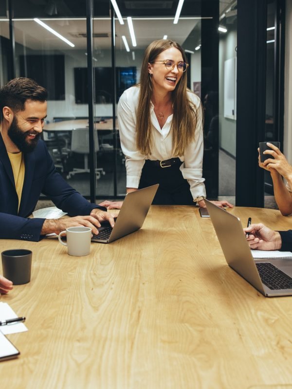 Colleagues laughing cheerfully during a meeting in a boardroom. Group of happy businesspeople enjoying working together in a modern workplace. Successful business professionals collaborating.